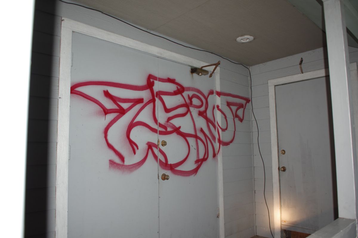 building with red text spray painted across double doors. text reads zero.